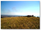 Parco dei Poggetti. Attrezzi ginnici nell'erba alta. Il fumo sulla destra  l'incendio al supermercato Conad di Rosignano Solvay del 12 luglio 2005 ore 16.