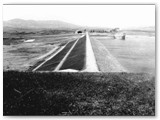 1965 - La diga in terra battuta a valle e rivestita in pietre lato lago. Al centro la strada di servizio